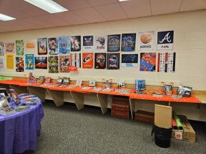 Picture of counter with books displayed and posters on wall.